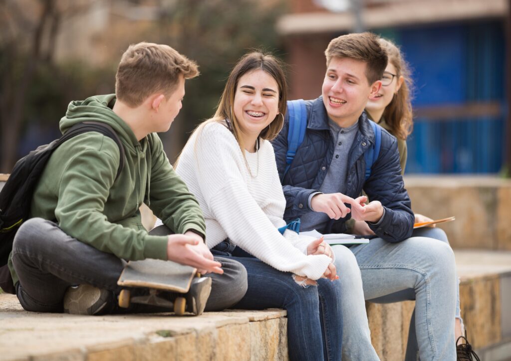 In this visual, there are 4 teenage children laughing and chatting. It represents the period of adolescence.