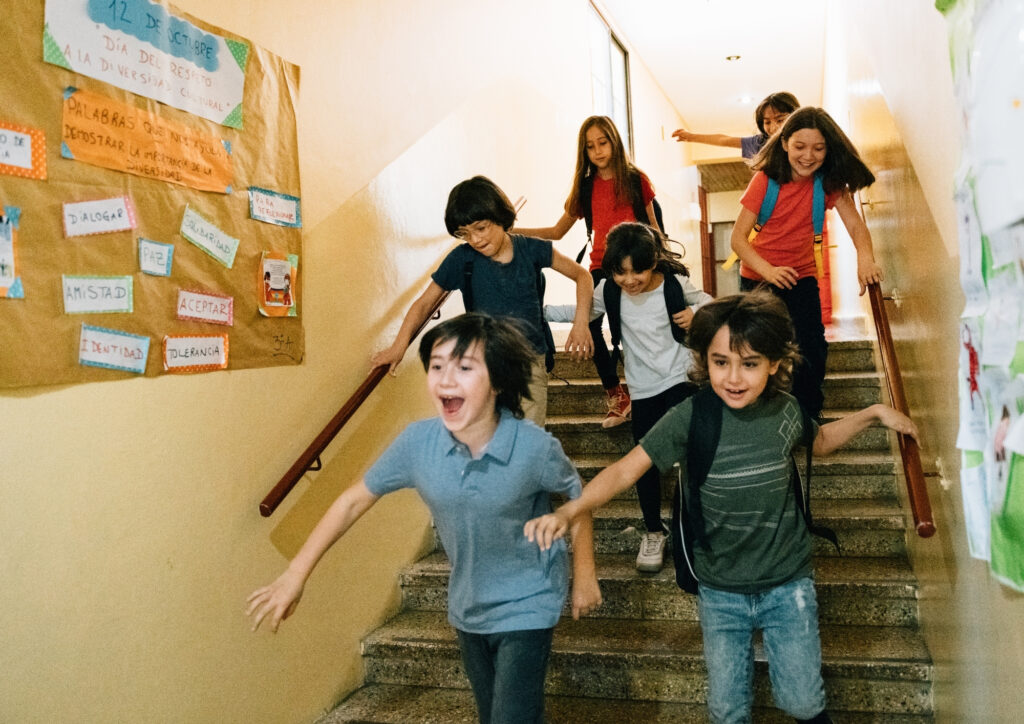 In the photo there are children running down the school stairs.