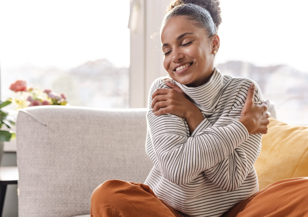 The photo shows a young woman hugging herself.