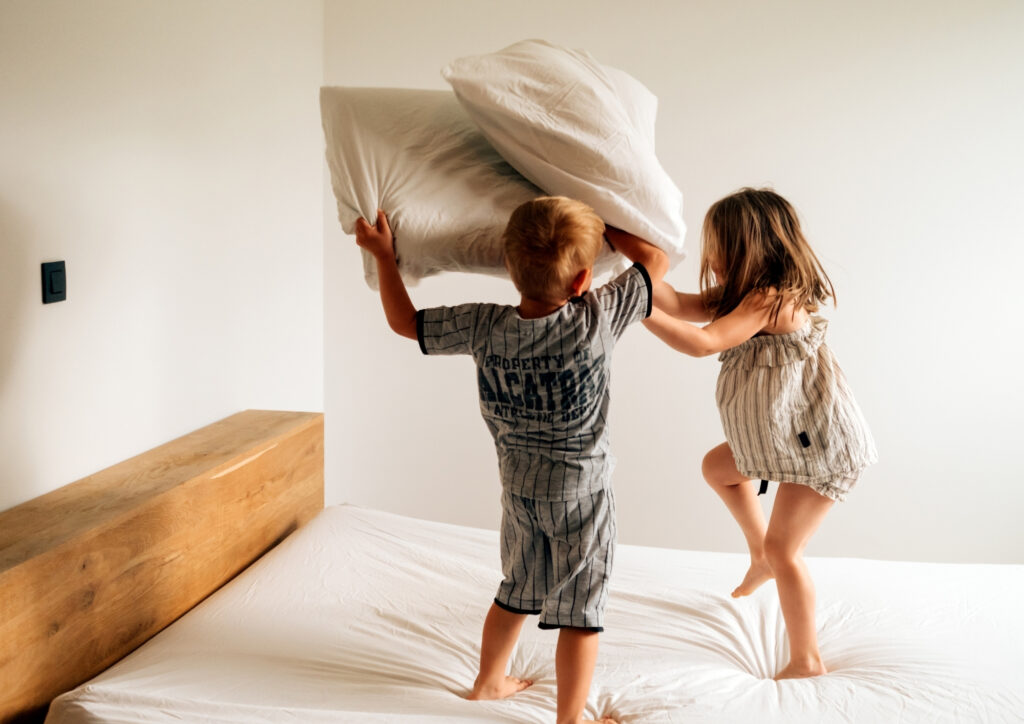 the photo shows two children playing jumping on the bed. 