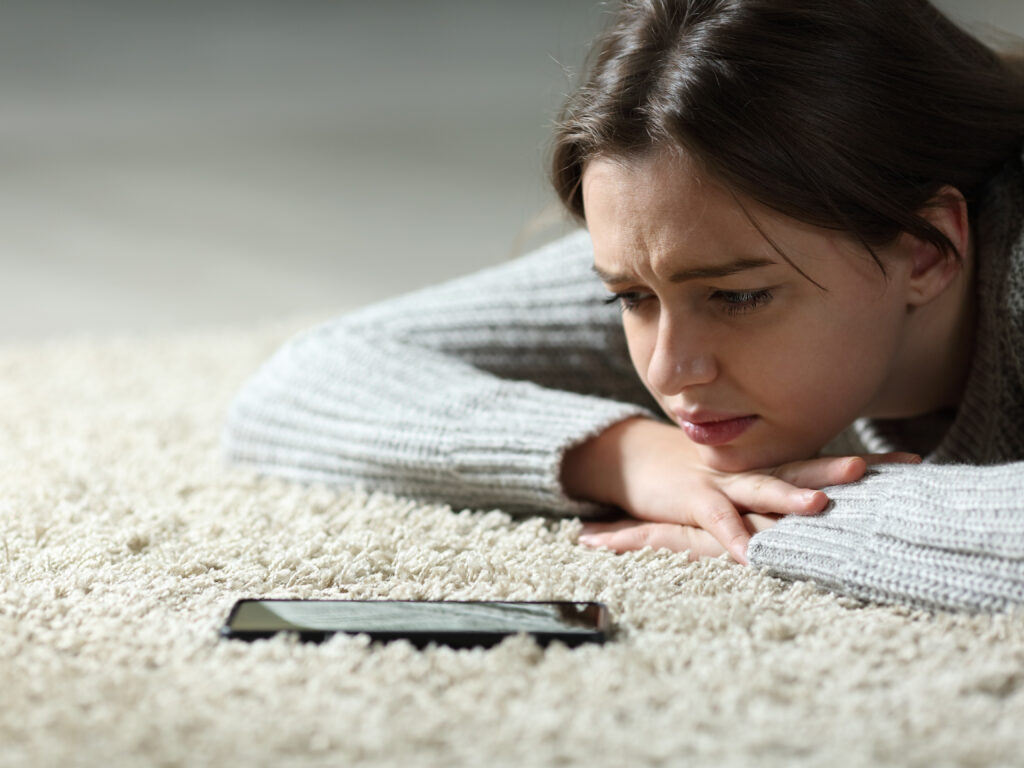 this photo is used to represent ghosting behavior in relationships. The photo shows a sad girl waiting a message by the phone