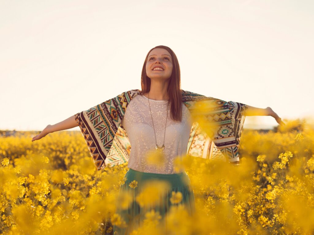 This photo is represent finding happiness. a woman in a field of flowers, looking happily at the sky.